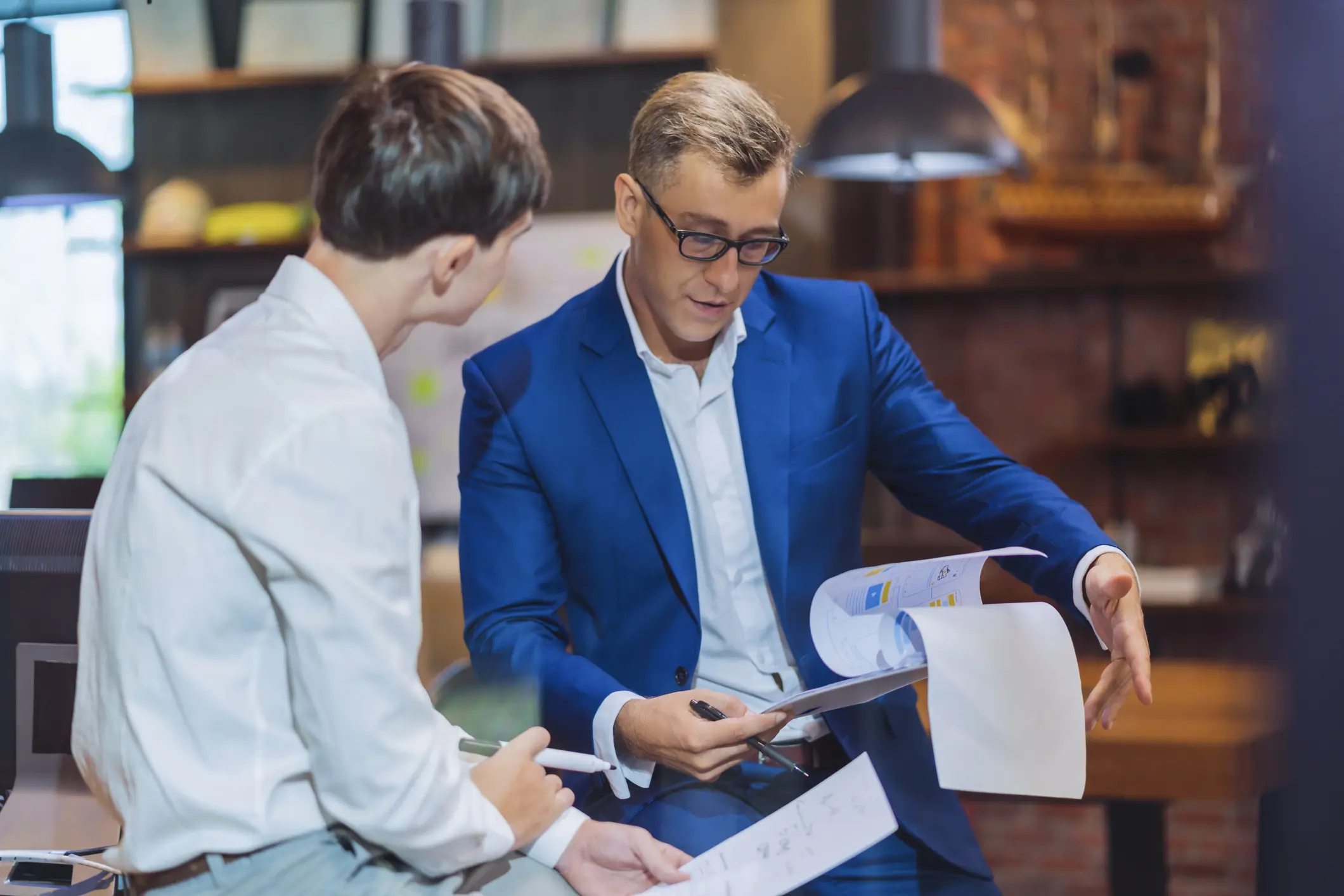 Two men discussing documents in office.