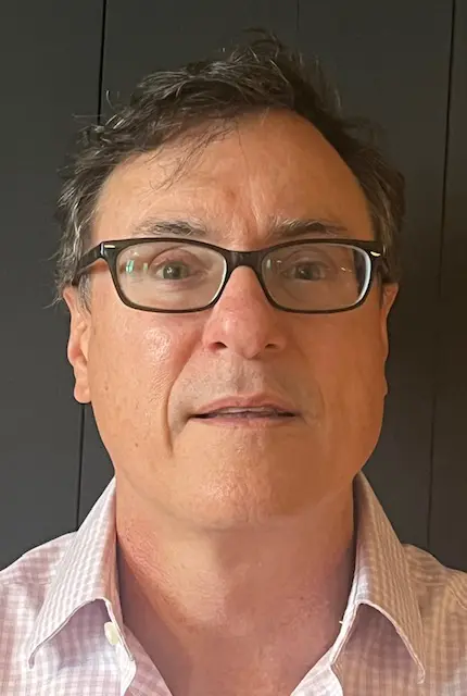Close-up portrait of a middle-aged man with glasses.