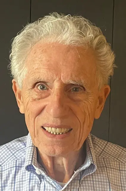 Smiling elderly man with white hair and blue eyes.